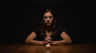 Femme seule à une table à la lumière d'une bougie, illustrant la vulnérabilité face à un medium et la nécessité de se protéger